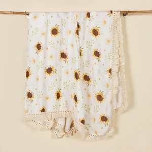 Close-up of baby muslin swaddle blanket with sunflower prints and crochet fringe edges