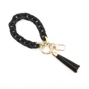 Close-up of black chunky acrylic link keychain with golden metal ring and leather tassel