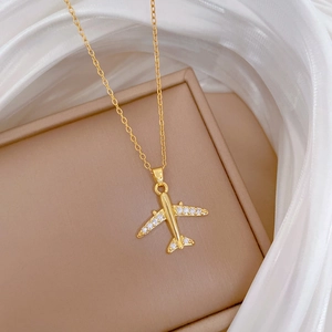 Detail of gold airplane pendant with pavé crystals on a beige jewelry display