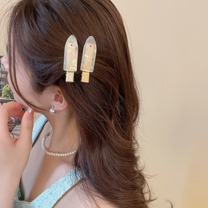 Close-up of candy-colored teardrop hair clips with gems on model's side hair