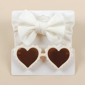 Detail of white knit bow headband and scalloped heart-shaped sunglasses on display card