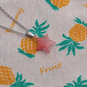 Close-up of pink star pendant on silver chain necklace over a cute pineapple fabric