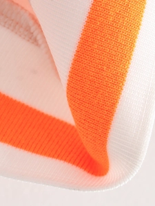 Gros plan des poignets élastiques rayés orange et blanc d'une veste de baseball
