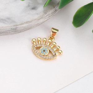 Macro shot of gold-plated evil eye pendant with blue and white crystals on marble base