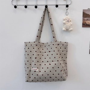 Close-up of canvas tote bag with burgundy polka dots and bow embroidery details