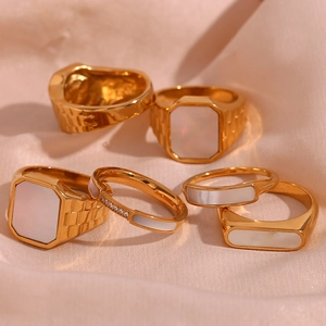 Set of gold-plated stainless steel rings with mother of pearl on beige silk fabric