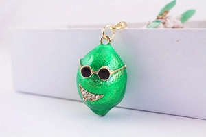 Dettaglio di un ciondolo a limone verde smaltato con occhiali da sole e sorriso di cristallo