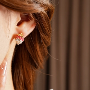 Close-up of vintage gold-plated strawberry earrings with sparkling zircon crystals on ear