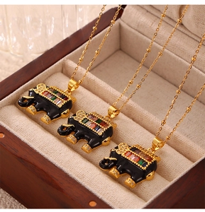 Three gold beaded necklaces featuring colorful rhinestone elephant pendants on wooden tray