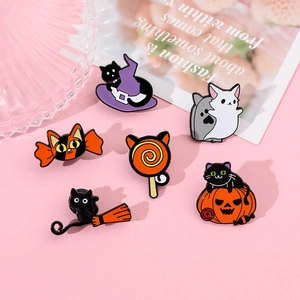 Flat lay of Halloween enamel pins featuring black cats with pumpkins and wizard hats