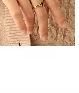 Bague chaîne dorée avec incrustation rectangulaire noire portée avec un pull en maille