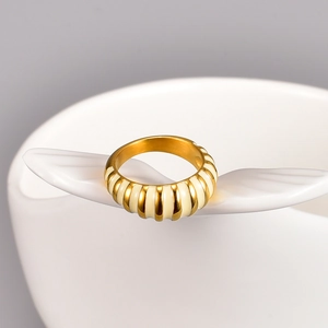 Vintage gold-plated totem ring with cream enamel vertical stripes on a white ceramic tray
