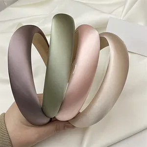 Detail of four padded satin headbands in muted purple, green, pink, and gold colors