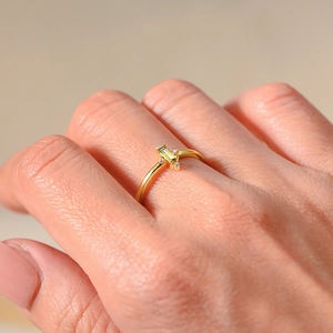 Macro shot of a gold square green zircon ring on finger with elegant side stones