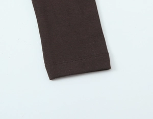 Détail du tissu en maille côtelée marron foncé montrant la texture et la couture de la manche