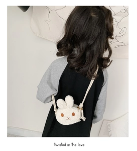 White plush bunny purse with brown embroidery and woven strap worn by a child