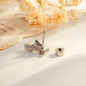 Christmas silver bow bell cartilage stud earring with sparkling crystals on soft backdrop