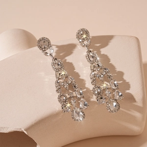 Macro detail of silver drop tassel earrings with sparkling crystals on stone stand