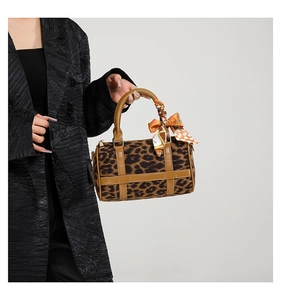 Detail of leopard print Boston bag with brown leather handles and decorative silk scarf