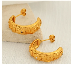 Detail of vintage gold C-shape earrings with sun and moon celestial relief patterns