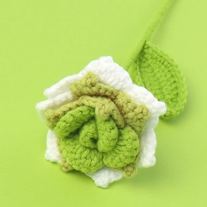 Macro shot of handcrafted white and green crochet rose made from high-quality wool yarn