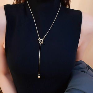 Detail of minimalist gold Y-necklace with OT toggle clasp and small ball pendant on black