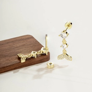 Vintage style coffee gold fishtail screw-back earrings with clear zircon stones on a wooden coaster