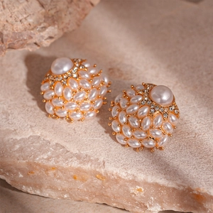 Close-up of vintage faux pearl and rhinestone cluster earrings on a textured stone base