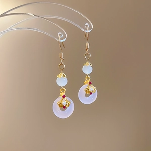 Détail de boucles d'oreilles crochet doré style national avec perle blanche et jade translucide