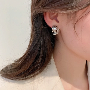 Close-up of geometric silver layered metal hoops worn on the ear showing a minimalist style