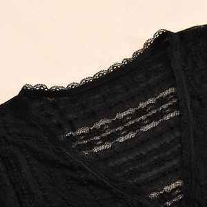 Detail of delicate black lace embroidery and scalloped neckline on long sleeve top