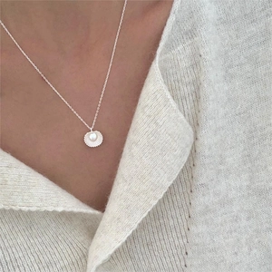 Close-up of a 925 sterling silver necklace with shell pendant and pearl on a model