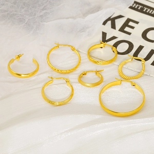 Detail shot of assorted gold hoop earrings with twisted and engraved patterns on white fabric
