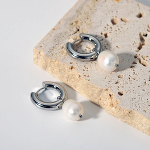 Detail of minimalist stainless steel hoop earrings with natural freshwater pearl pendants