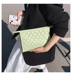 Detail of light green quilted pouch bag with diamond stitch pattern and zip closure