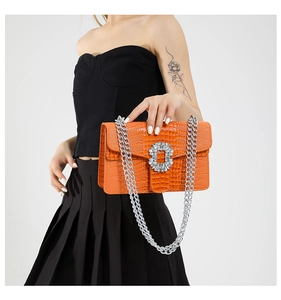 Detail of orange crocodile pattern crossbody bag with silver chain and diamond buckle