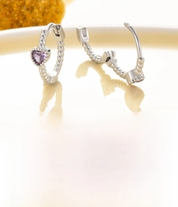 Detail of silver heart hoop earrings with purple zircon and twisted metal texture