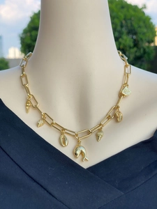 Dettaglio di ciondoli a forma di delfino e conchiglia in oro 18k su collana a maglie