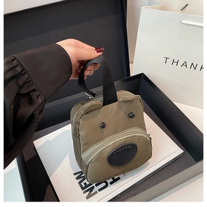 Close-up of army green nylon mini handbag with cartoon bear ears in a gift box setup