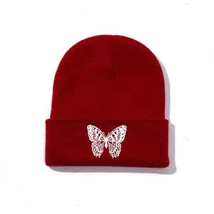 Close-up of white butterfly embroidery on a dark red knitted beanie hat cuff