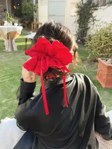 Close-up of red lace scrunchie with long ribbons worn outdoors by a model