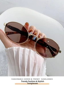 Detail of oval sunglasses with gold metal frame, brown lenses and tortoiseshell tips