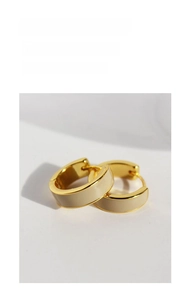 Macro detail of gold-toned hoop earrings with smooth beige enamel finish and secure clasp
