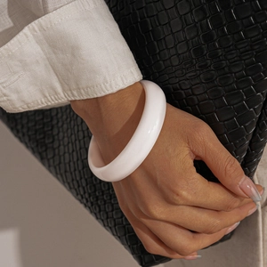 Detail of a minimalist white resin bangle with a smooth polished finish and round geometry