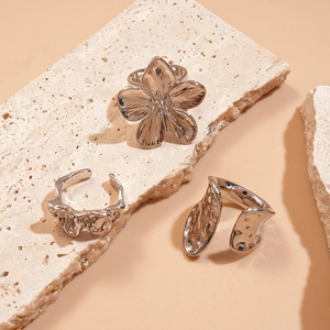 Detailed view of silver ruffled floral and irregular geometric open rings on stone base