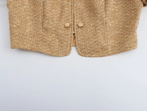 Detailed close-up of brown tweed fabric with shimmering sequins and fabric-wrapped buttons