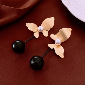 Detailed shot of butterfly pearl earrings with gold plating and black beads on silk