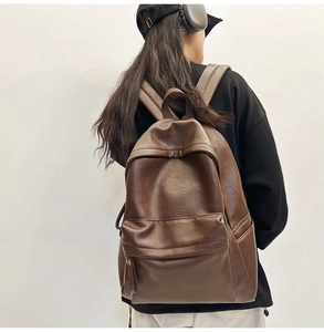 Detailed view of the dark brown leather backpack's texture and front pocket on a model