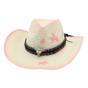 Detail of straw cowboy hat featuring pink stars, ethnic band and metal bull skull