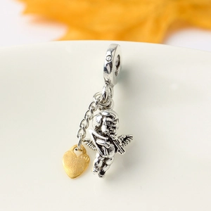 Elegant silver pendant featuring a golden Cupid heart charm displayed on a white plate